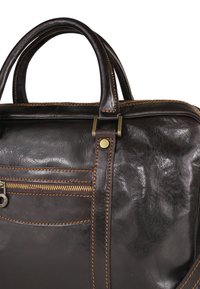 Brown leather bag with smooth texture, dual handles, decorative stitching, a front zip pocket, and bronze hardware accents.
