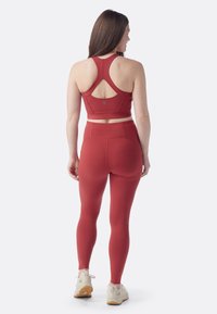 Karmosinröd sportcrop top och högmidjade leggings i stretchtyg. Har en racerryggdesign och sömlös konstruktion.