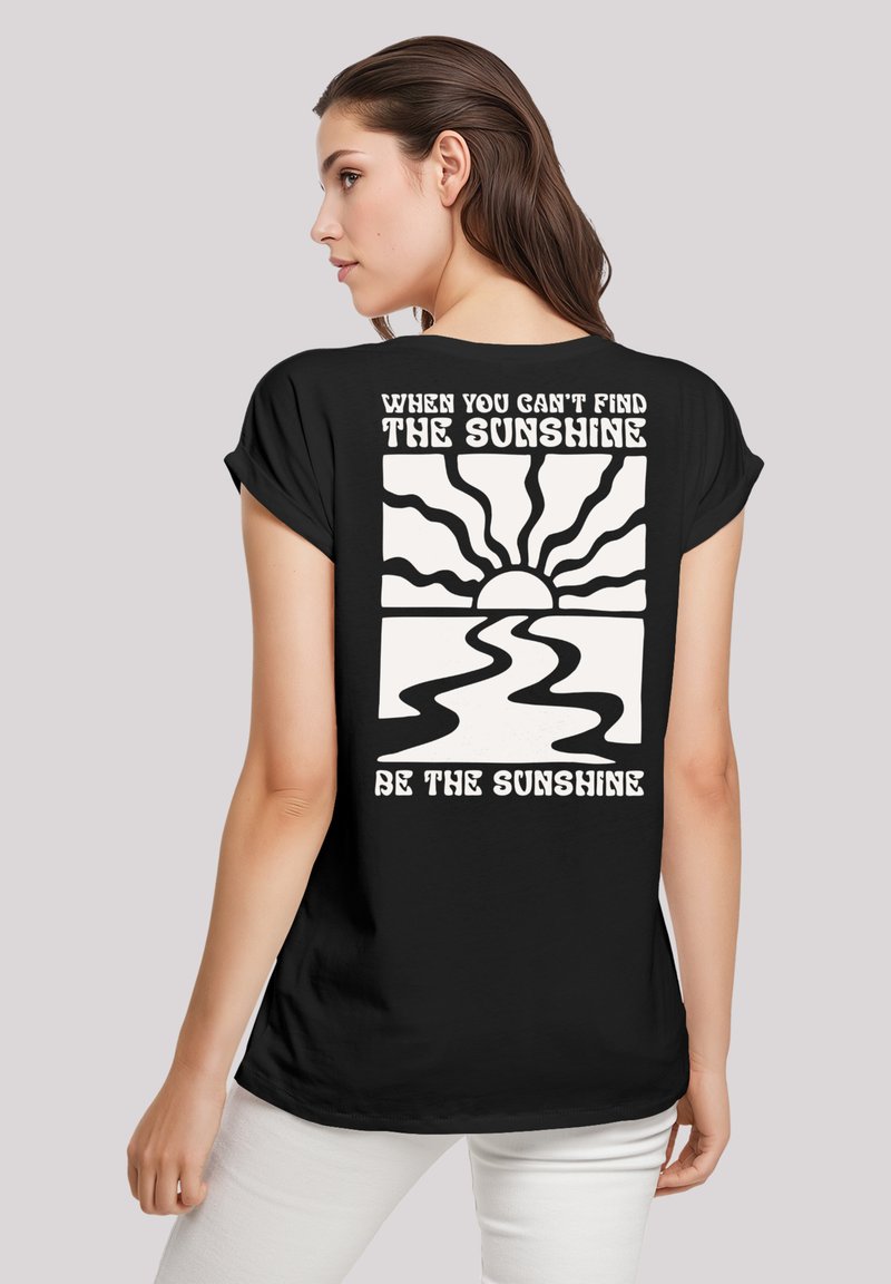 Black t-shirt featuring a white sun graphic with rays, accompanied by text: "When you can't find the sunshine, be the sunshine."