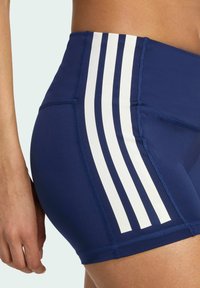 Granatowe szorty sportowe z wysokim stanem, z trzema pionowymi białymi paskami z boku i płaskimi szwami dla większej trwałości.