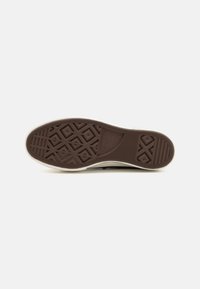 Suela de zapato de goma marrón con un patrón de diamante y superficie texturizada; presenta un borde blanco contrastante para estabilidad y agarre.