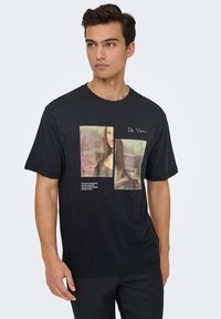 Sort bomulds-t-shirt med et grafisk tryk af Mona Lisa, med to overlappende sektioner og teksten "Da Vinci" over billedet.