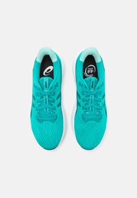 Baskets de sport teal avec une tige en maille texturée, semelles blanches et accents sombres contrastants. Présentent un système de laçage et des semelles intérieures avec logo.