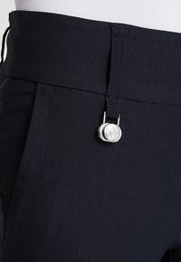 Mörkblå byxor med en elegant design, texturerad tyg och en silverfärgad knappstängning i midjan. Skräddarsydd passform med bälteshällor.