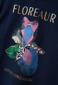 Marineblauwe stof met een bloemenpatroon met gouden, roze, blauwe en groene elementen; bevat pailletten en tekst die zegt "FLORAUR LOVERS & DREAMERS."