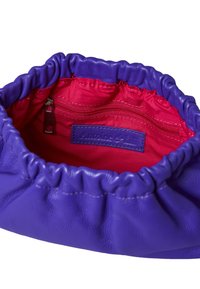 Purple leather handbag with a gathered top, featuring a smooth exterior, a red satin interior, and a small zipped pocket inside.