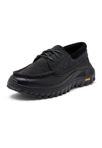 Schwarzer robuster Schnürschuh mit dicker Vibram-Laufsohle und wildlederartigem Obermaterial.