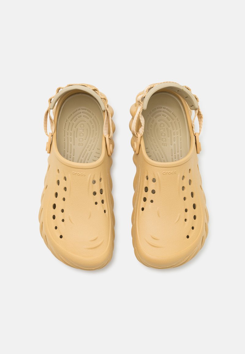 Sabot gialli in gomma con cinturino posteriore, fori di ventilazione e soletta texturizzata. Superficie liscia con punta arrotondata e suola ondulata.