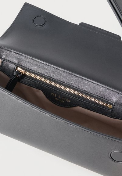 Ανοικτή γκρι δερμάτινη τσάντα που δείχνει εσωτερική τσέπη με φερμουάρ σε μαύρο χρώμα και χρυσό φερμουάρ με ετικέτα "Rae & Doll New York".