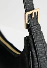 Tracolla in tessuto nero con hardware in tonalità dorata. Presenta una fibbia rettangolare e dettagli cuciti lungo i bordi.
