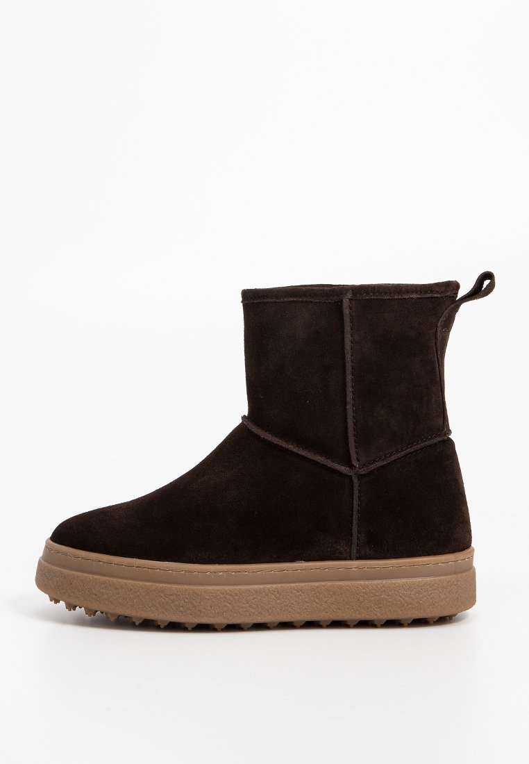 Braune Wildleder-Ankle-Boots mit einer strukturierten Gummisohle. Ausgestattet mit einer Ziehschlaufe und einfachen Nahtakzenten, entworfen für Komfort und legere Trageweise.