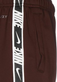 Nike šorti bordo krāsā ir aprīkoti ar elastīgu jostu, sānu kabatām un izteiktu balto logo svītru. Viegls un elpojošs materiāls.