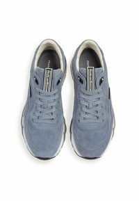 Blaue Wildledersneaker mit abgerundeter Spitze, strukturiertem Obermaterial, Schnürverschluss und kontrastierendem schwarz-weißem Markenlogo auf der Zunge.