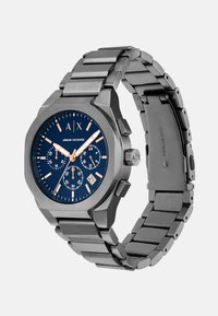 Sat od nehrđajućeg čelika s osmerokutnim kućištem, plavim brojčanikom, naglascima od ružičastog zlata, funkcijama kronografa i narukvicom od karika.