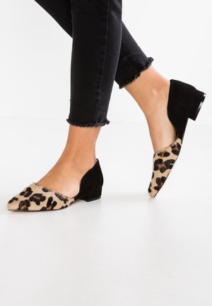 Leopard-print flat shoes with a black suede heel and trim, featuring a pointed toe and contrasting textures. Ankle-length black jeans.