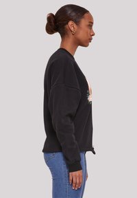 Schwarzer Hoodie mit lässiger Passform, der ein florales Design auf der Vorderseite, gerippte Bündchen und einen Kordelzugsaum für Anpassungsmöglichkeiten bietet.