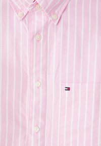 Light pink button-up shirt with white stripes, featuring a classic collar, six buttons, and a chest pocket with a logo detail.