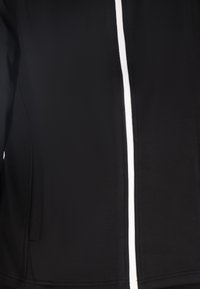 Schwarze Jacke mit einer glatten Textur, ausgestattet mit einem weißen Reißverschluss und Seitentaschen. Das Design betont einen schlanken, modernen Look.