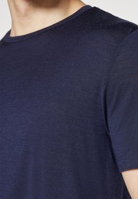 Navy blue short-sleeve t-shirt with a smooth texture and a crew neckline, featuring subtle variations in fabric thickness.