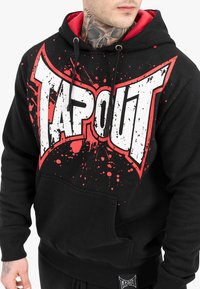 Black hoodie with red accents, featuring a large "TAPOUT" graphic in white and red splatter design; includes a front pocket and ribbed cuffs.
