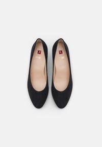 Black suede pumps with a pointed toe and smooth interior, featuring a small gold logo and a contrasting red square on the insole.
