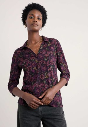 Chemise à manches longues florale en tissu sombre avec des motifs violets et verts, présentant un col et un style à boutons.