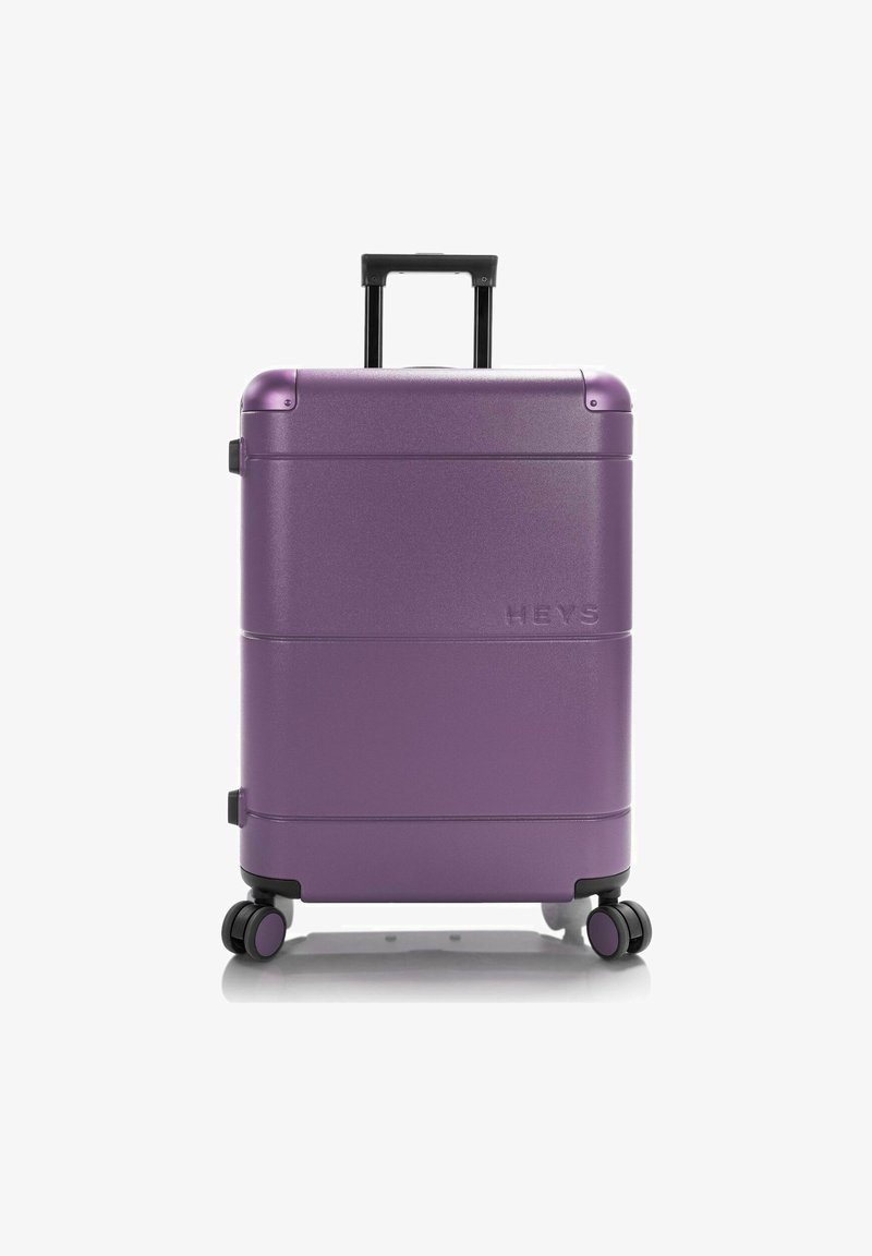 Valigia rigida di colore viola metallico, dotata di manico telescopico, quattro ruote e logo del marchio in rilievo. Superficie liscia con una leggera trama.
