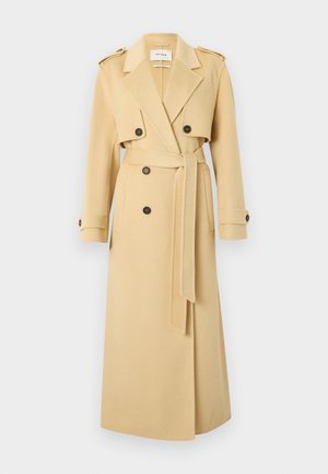 Lange beige trenchcoat met brede revers, dubbele rij knopen, tailleband en met knopen te sluiten mouwbandjes, weergegeven op een witte achtergrond.