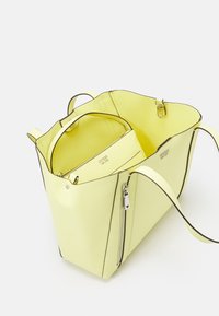 Gele nepleren draagtas met zwarte bies, voorzien van een binnenvak met rits en een extra kleinere etui binnenin voor organisatie.