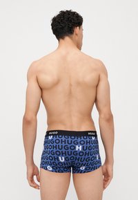 Heren trunk ondergoed in blauw met herhaald patroon van het "HUGO" logo. Zachte katoenmix, elastische zwarte tailleband, getailleerde pasvorm.