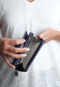 Marineblauwe leren portemonnee met een ritsafsluiting, met een lichtgrijze binnenkant met driehoekige patronen en meerdere kaartsleuven.