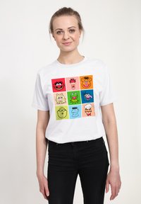 Hvid bomulds T-shirt med en grafik af ni tegneserieansigter i levende farver på et kvadratisk gitterdesign.
