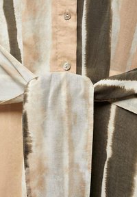 Gestreepte overhemdd met beige, crème en olijfgroene kleuren. Beschikt over een striktaille detail en een gladde stof textuur. Knopen zijn zichtbaar.