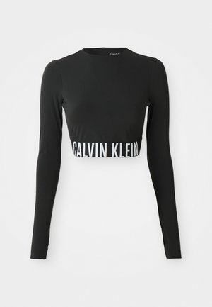Top nero a maniche lunghe corto con collo alto e banda con logo "Calvin Klein" bianca attorno alla vita.