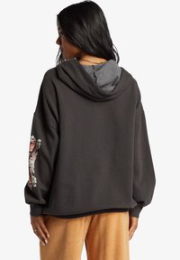 Sudadera oversized de mujer en gris oscuro con un forro interior gris, con bordado floral en la manga izquierda y puños y dobladillo de canalé.