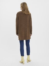 Brown oversized sweater with a soft texture, paired with blue slim jeans and yellow block-heeled ankle boots. Simple and modern design.