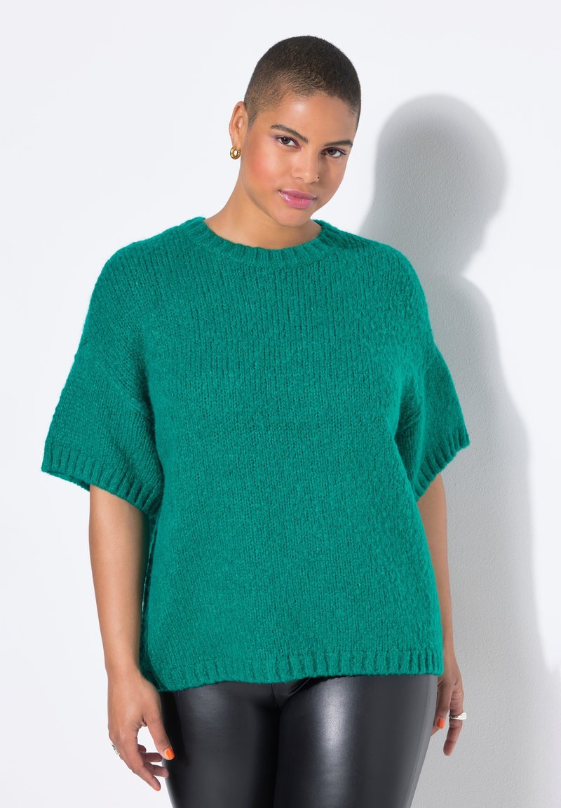 Teal oversized striktrøje med korte ærmer, tekstureret finish og ribbet halsudskæring, parret med sorte nederdelbukser i faux læder.