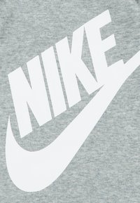 Hanorac gri melanj cu un logo mare „NIKE” alb și design swoosh, realizat dintr-un material moale, texturat, cu finisaj ribetat.