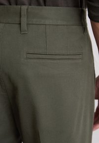 Pantalons vert olive en coton avec une texture lisse, dotés d'une poche arrière et d'une taille ajustée.
