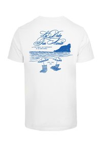 White cotton t-shirt featuring a blue graphic design of beach chairs and umbrellas with text, "La Dolce Far Niente," and "Capri, Italy 1990."