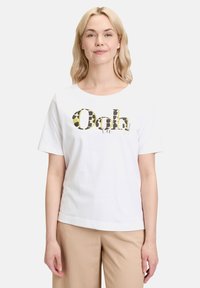 T-shirt en coton blanc avec un grand graphisme coloré "Ooh" rehaussé de motifs animaliers. Manches courtes et col rond.