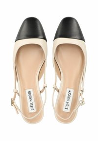 Beige og svarte slingback hæler med spiss tå og teksturert skinn. Har et tynt ankelrem og en polstret såle.