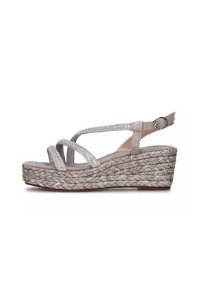 Sandali con zeppa caratterizzati da una tomaia in morbido suede grigio chiaro con cinturini incrociati in glitter, una piattaforma intrecciata in juta e una chiusura con fibbia sulla cinghia alla caviglia.
