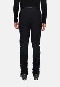 Zwarte skibroeken met een strakke pasvorm, gemaakt van een soepele, rekbare stof. Voorzien van ritszakken en versterkte onderste benen.