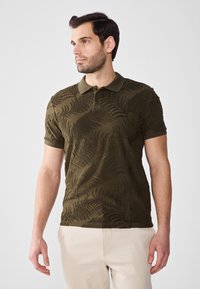 Olivenfarget polo skjorte med teksturert bregne-mønster, tre-knappers placket og en myk krage. Korte ermer og en skreddersydd passform.
