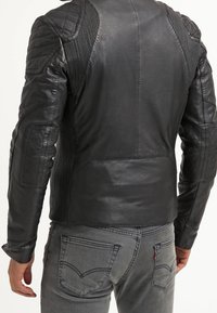 Svart lädermotorcykeljacka med kviltade axlar och ribbade detaljer, med en jämn yta och slim-fit design.