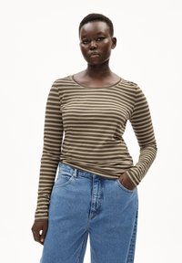 Langärmeliges gestreiftes Oberteil in Olive und Tan aus weichem Stoff, kombiniert mit hoch taillierten blauen Jeans mit klassischem Schnitt und Taschen.