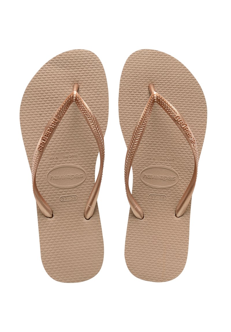 Tan gummifleksible flip-flops med en teksturert såle og rosegullremmer med vevd design. Merking synlig på sålen.