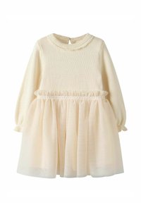 Haut crème en tricot avec encolure ronde et manches bouffantes, superposé à une jupe en tulle beige transparent avec une taille froncée et des détails à volants.