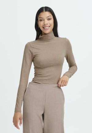 Langärmliges, braunes Rollkragenoberteil aus einem weichen Material, enganliegendem Design. Kombiniert mit hellbraunen, gestreiften Weitbein-Hosen.